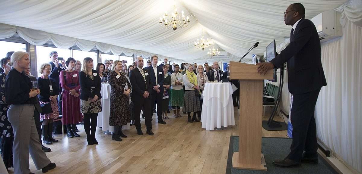 Kwasi_speaking Image of Houses of Parliament with SUDC "lets shine a light on SUDC" logo